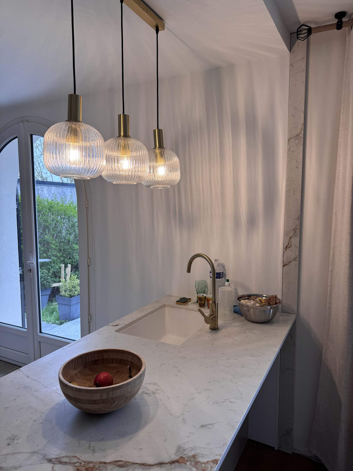 Îlot de cuisine sur mesure avec plan de travail clair et robinetterie, ouvert sur le jardin
