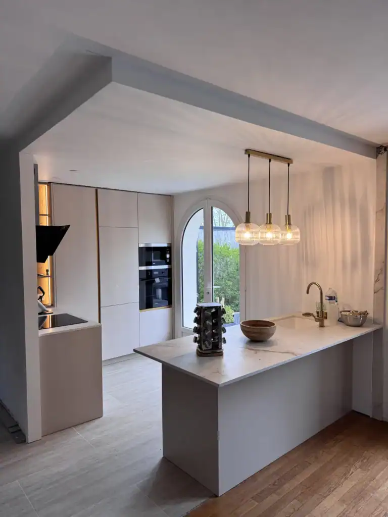 Cuisine sur mesure beige à Rambouillet avec îlot central effet marbre et façades sans poignées