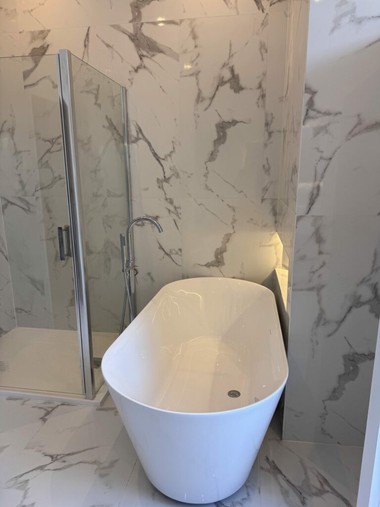 Salle de bain avec baignoire îlot et murs effet marbre